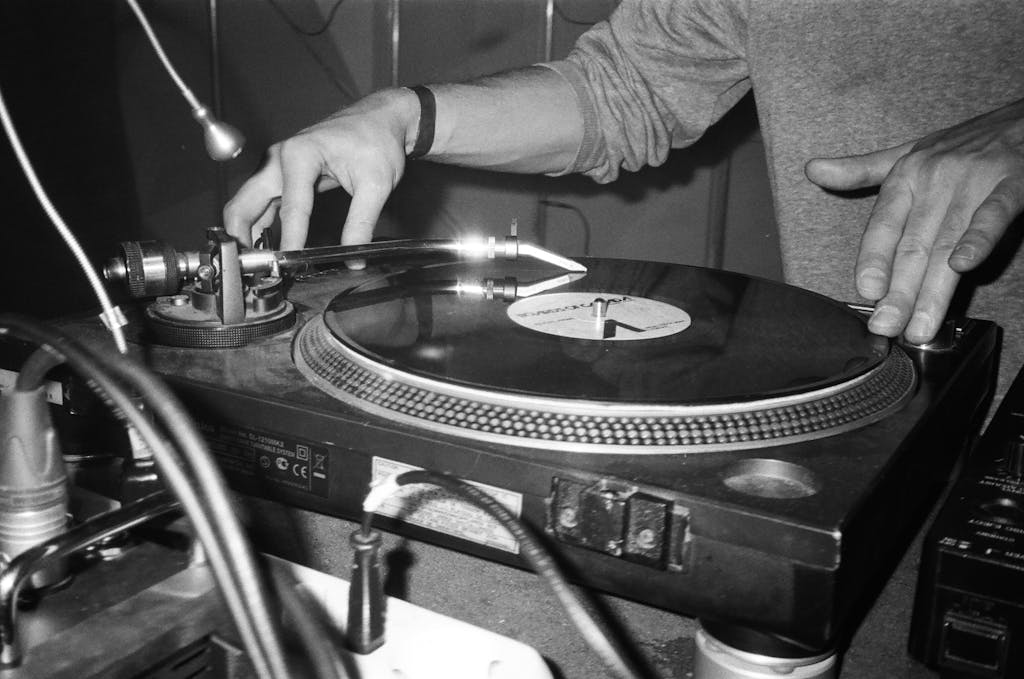 Close-up of a DJ using a turntable to play vinyl records, showcasing music equipment.
