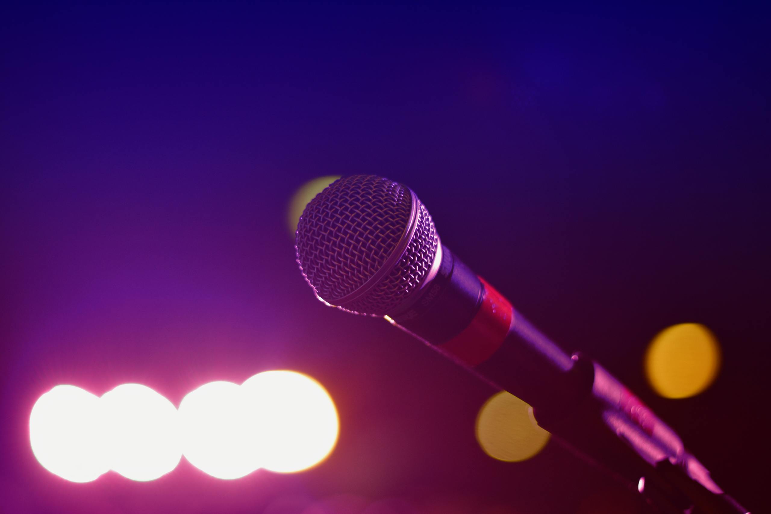 Colorful stage lighting highlights a microphone in a close-up view, perfect for music and performance themes.