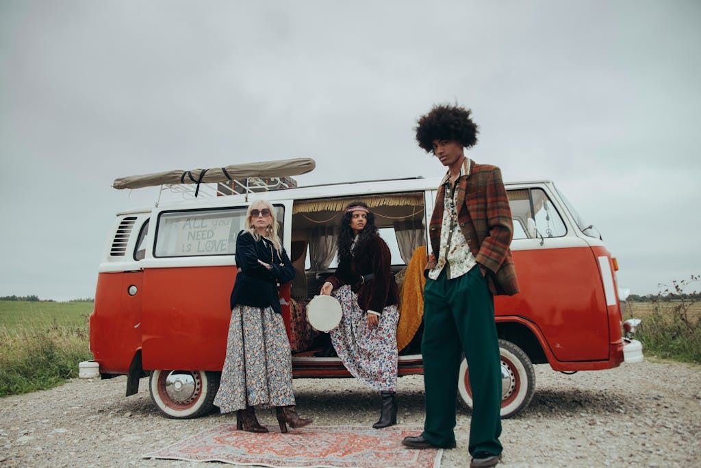 A diverse group posing with a vintage van, showcasing retro hippie style outdoors.