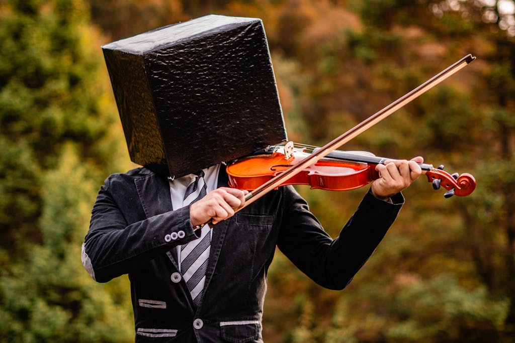 A surreal portrait of a man with a box on his head playing a violin in a forest setting.
