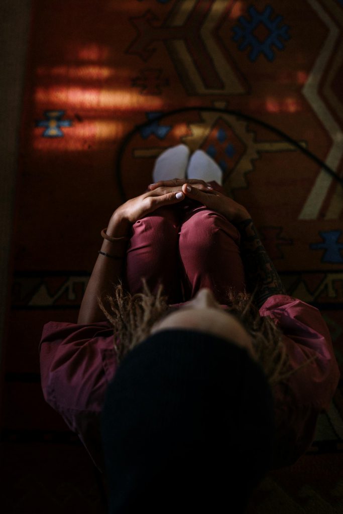 A woman relaxes indoors, lying on an artistic rug, enjoying a serene moment. Perfect for lifestyle and home themes.