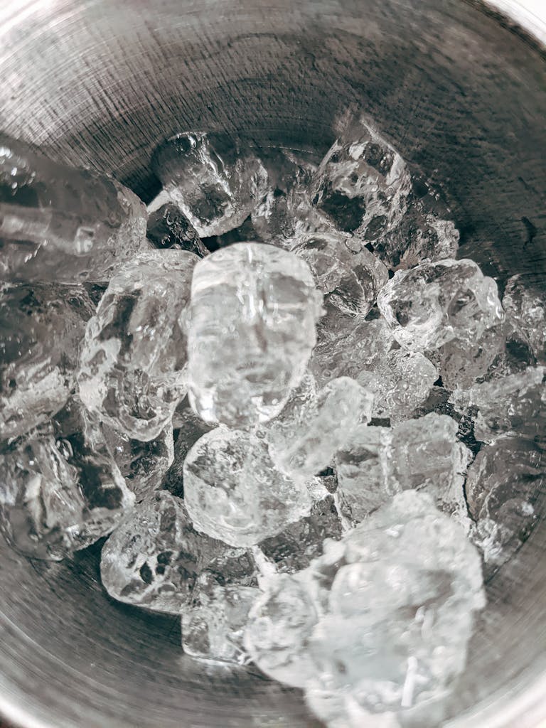 Clear ice cubes in a metal bowl, showcasing texture and detail.