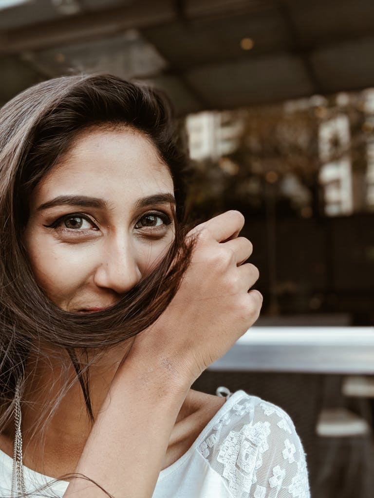 Close-up portrait of a woman smiling playfully while covering her face with her hair.