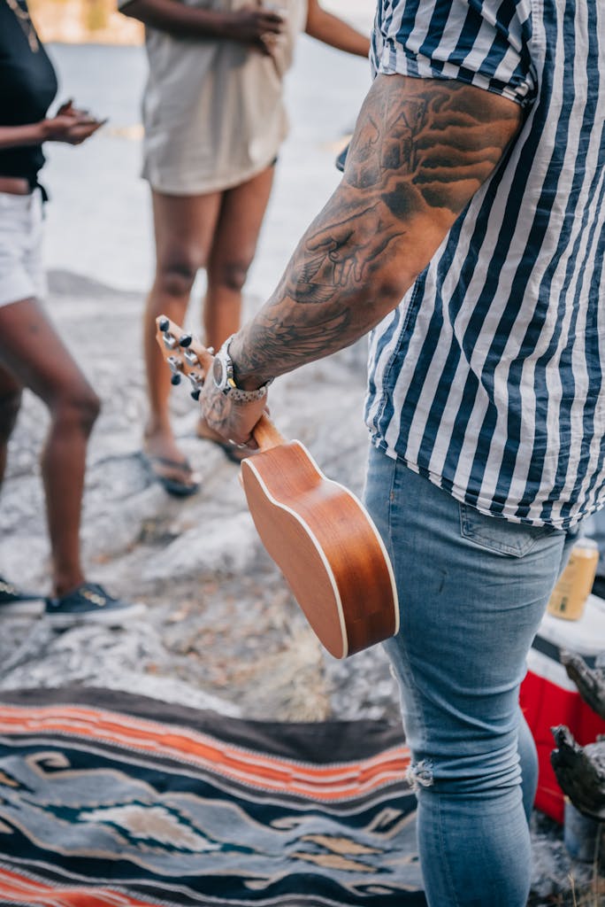 Friends gathered on the beach, playing music with a ukulele, embodying summer and leisure vibes.