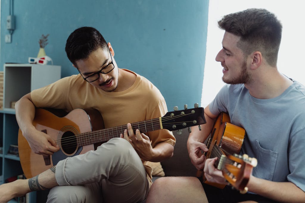 Two friends playing acoustic guitars and singing indoors, creating a joyful atmosphere.