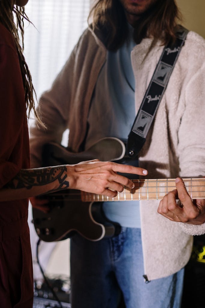 Two musicians collaborate in a home studio, focusing on guitar practice with attentive detail.
