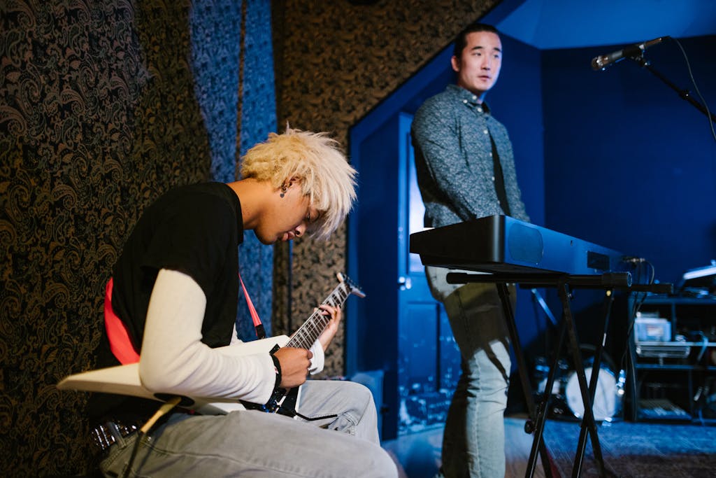 Two musicians practicing indoors with an electric guitar and keyboard, focusing on performance and creativity.