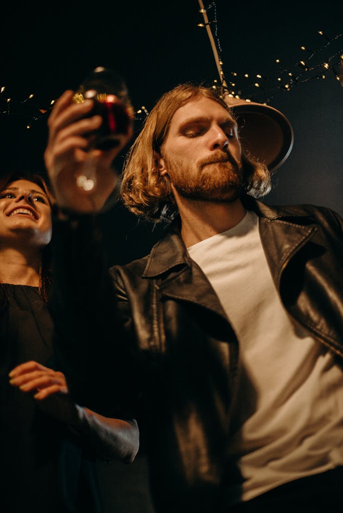 Young adults enjoying a party indoors, holding wine glasses and celebrating.