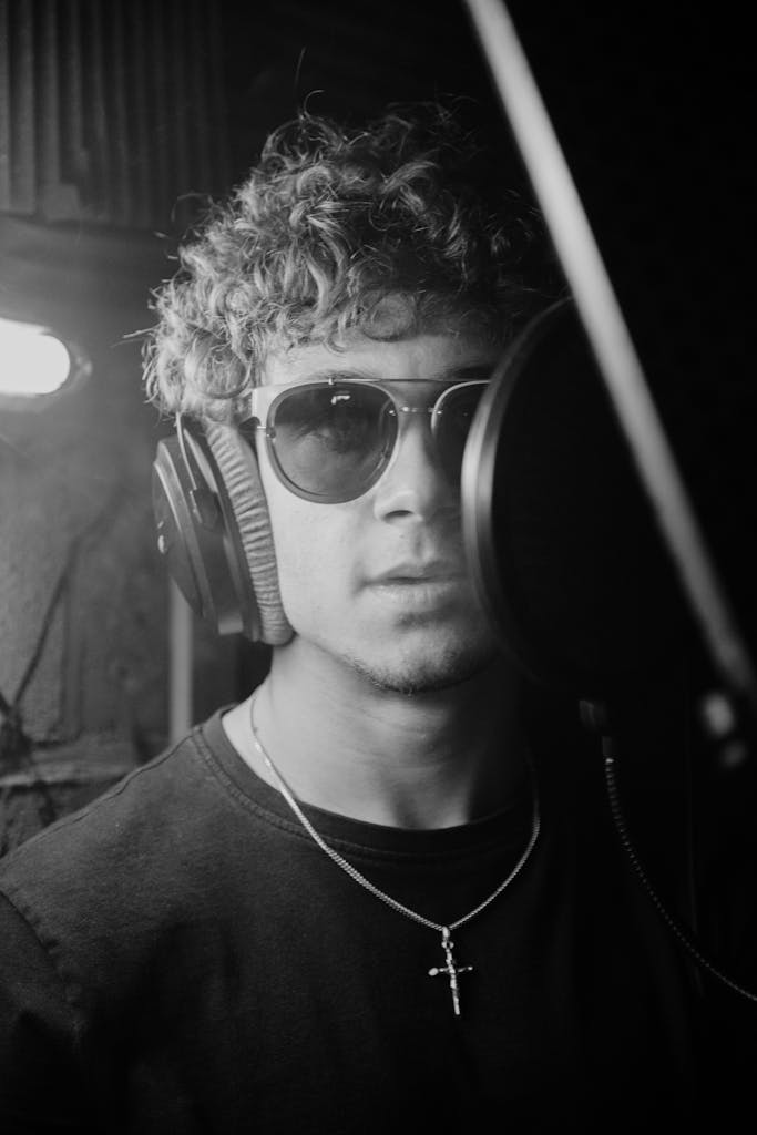 Black and white portrait of a man with headphones in a recording studio using coping skills learned in therapy at Musician Therapy Collective